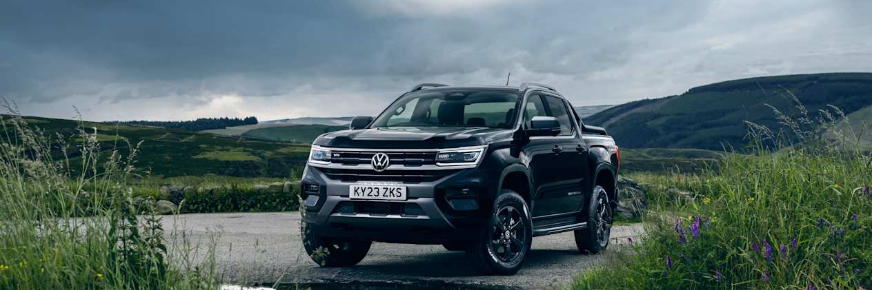 Black Volkswagen Amarok faces the camera with the Scottish countryside in the background