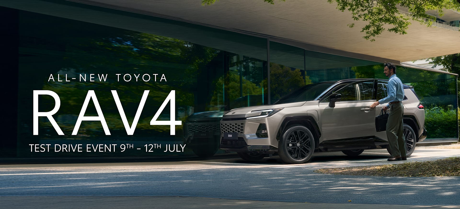 A man in a blue shirt approaches the all-new Toyota RAV4 parked under a modern structure.