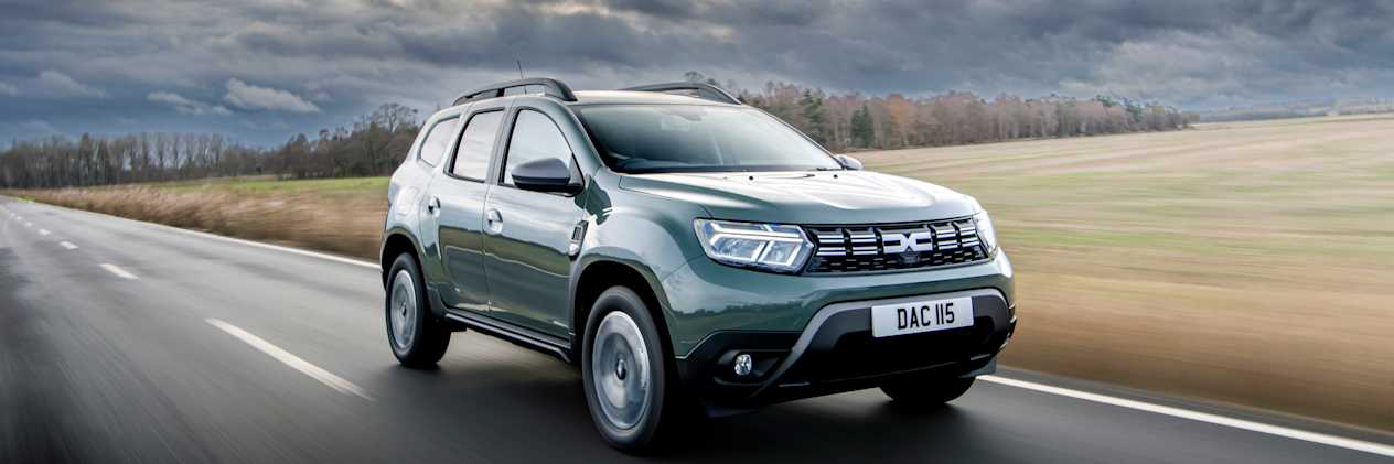 Green Dacia Duster driving along a road in the countryside