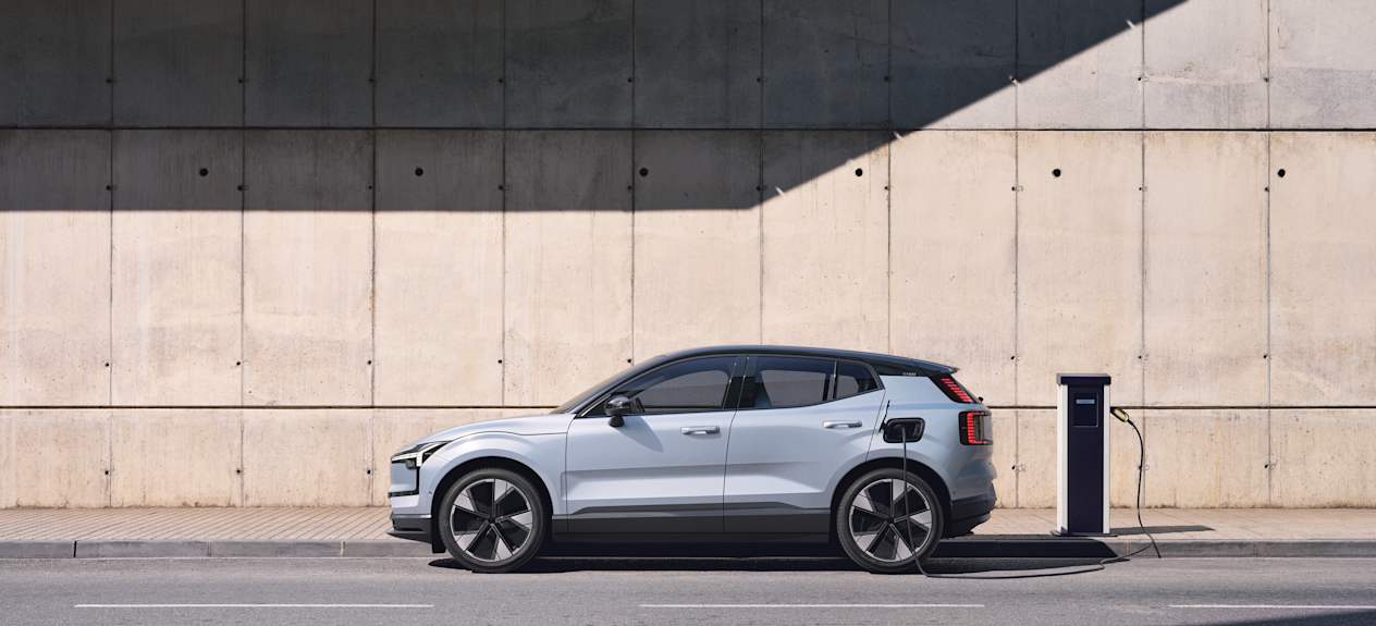 A grey Volvo EX30 parked and plugged into a charging point