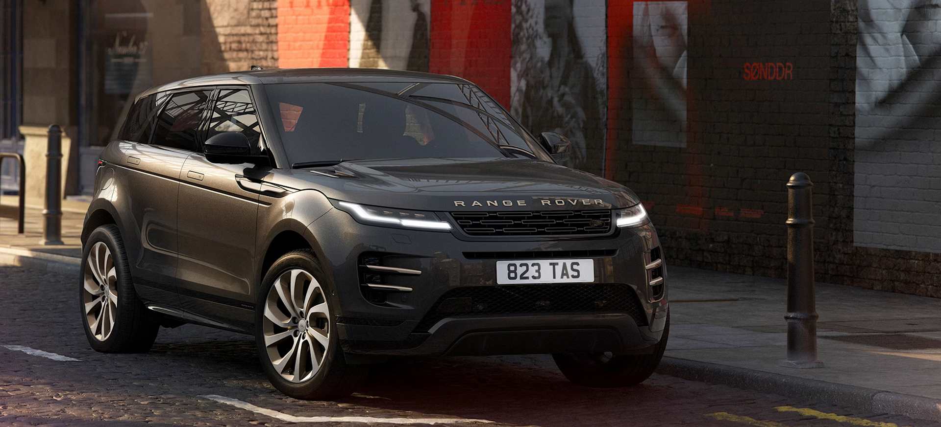 A sleek grey Range Rover Evoque Hoxton Edition parked on a cobblestone street with urban artwork in the background.