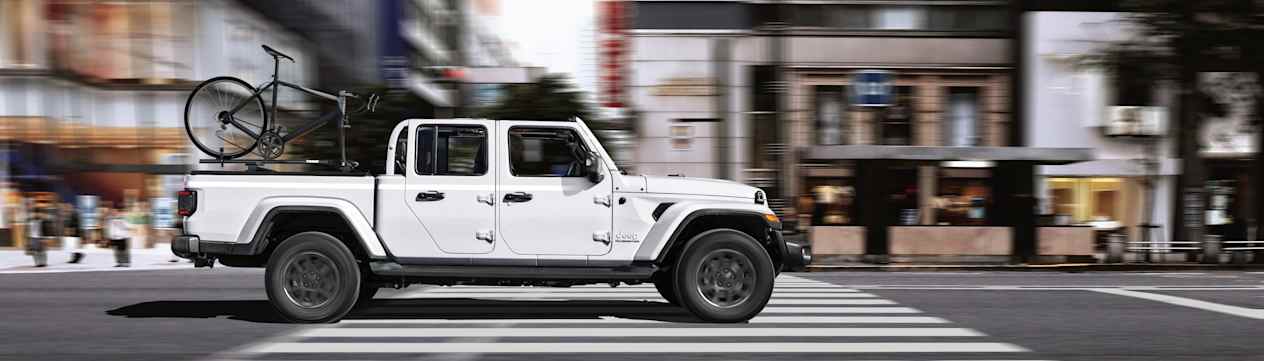 Jeep Gladiator 2022 : blanc vu de profil en ville avec vélo dans la benne