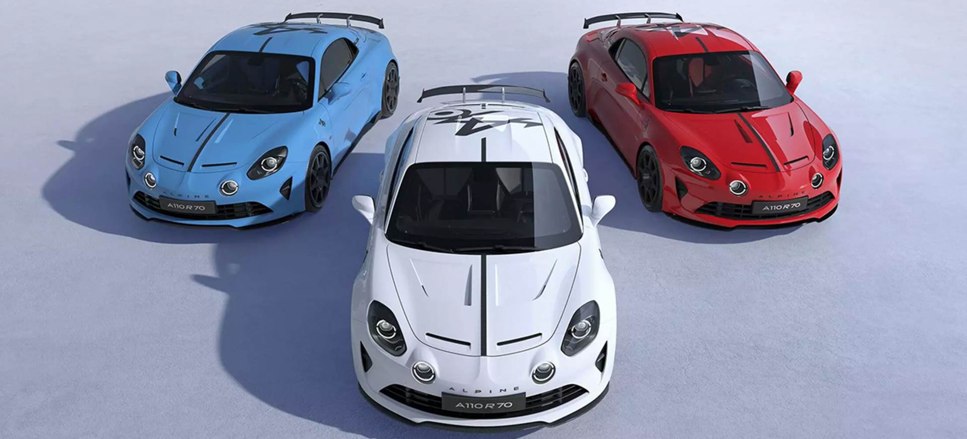 Three Alpine A110 cars in blue, white, and red parked on a snowy surface, showcasing their sleek designs.