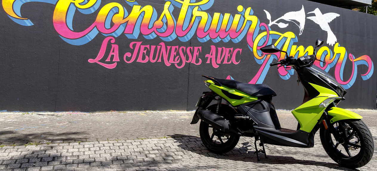 Kymco Super 8 R 2024 : trois quarts avant droit statique devant street art