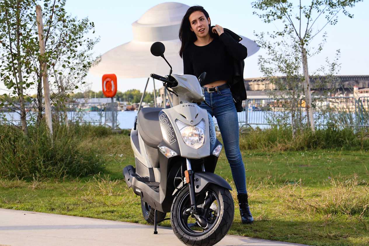 Kymco Agility 50 2024 : face avant statique avec jeune femme et phare allumé