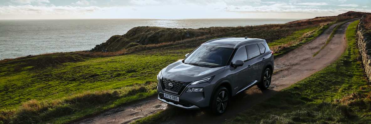 Grey Nissan X Trail on a rugged coastal road