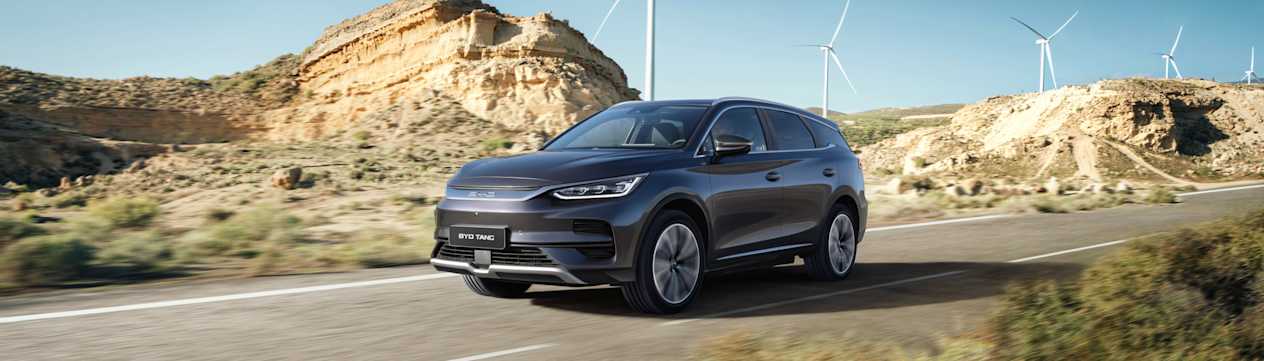 BYD Tang 2024 : trois quarts avant droit sur route avec éoliennes