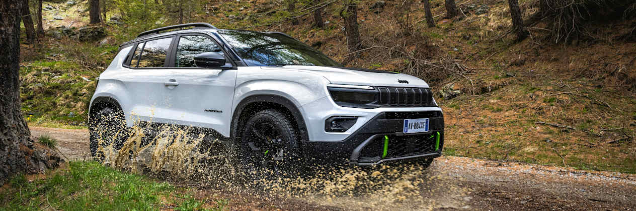 Jeep Avenger 4xe 2024 : trois quarts avant droit traverse une flaque sur une chemin en forêt