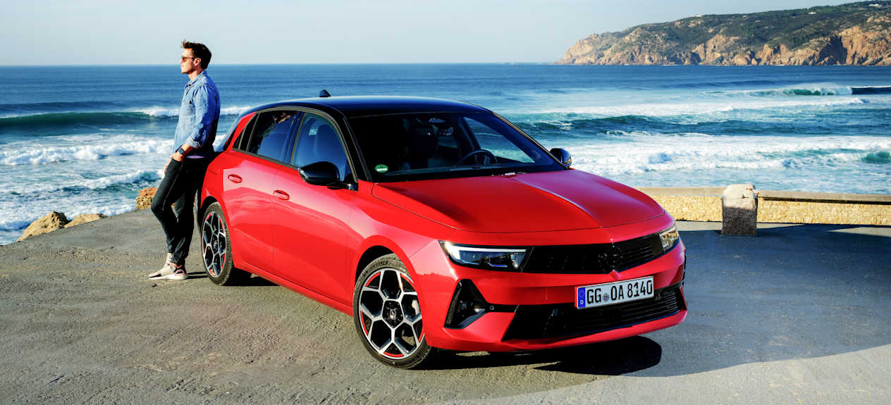 Opel Astra 2022 : trois quarts avant droit statique en bord de mer avec modèle