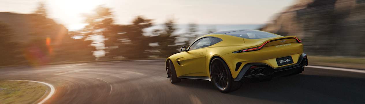 Aston Martin Vantage 2024 : trois quarts arrière gauche en virage sur route