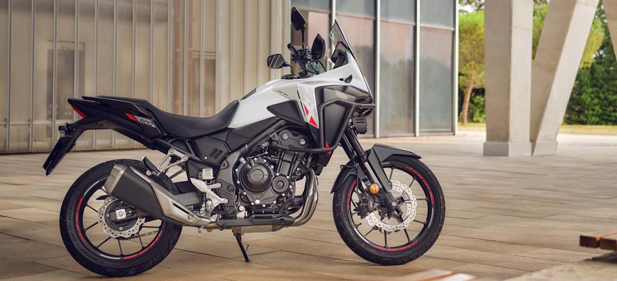 Honda NX500 2024 : profil droit statique devant bâtiment