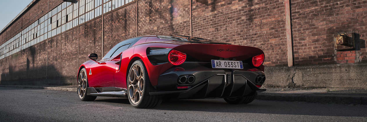 Alfa Romeo 33 Stradale 2023 : trois quarts arrière gauche devant bâtiment industriel