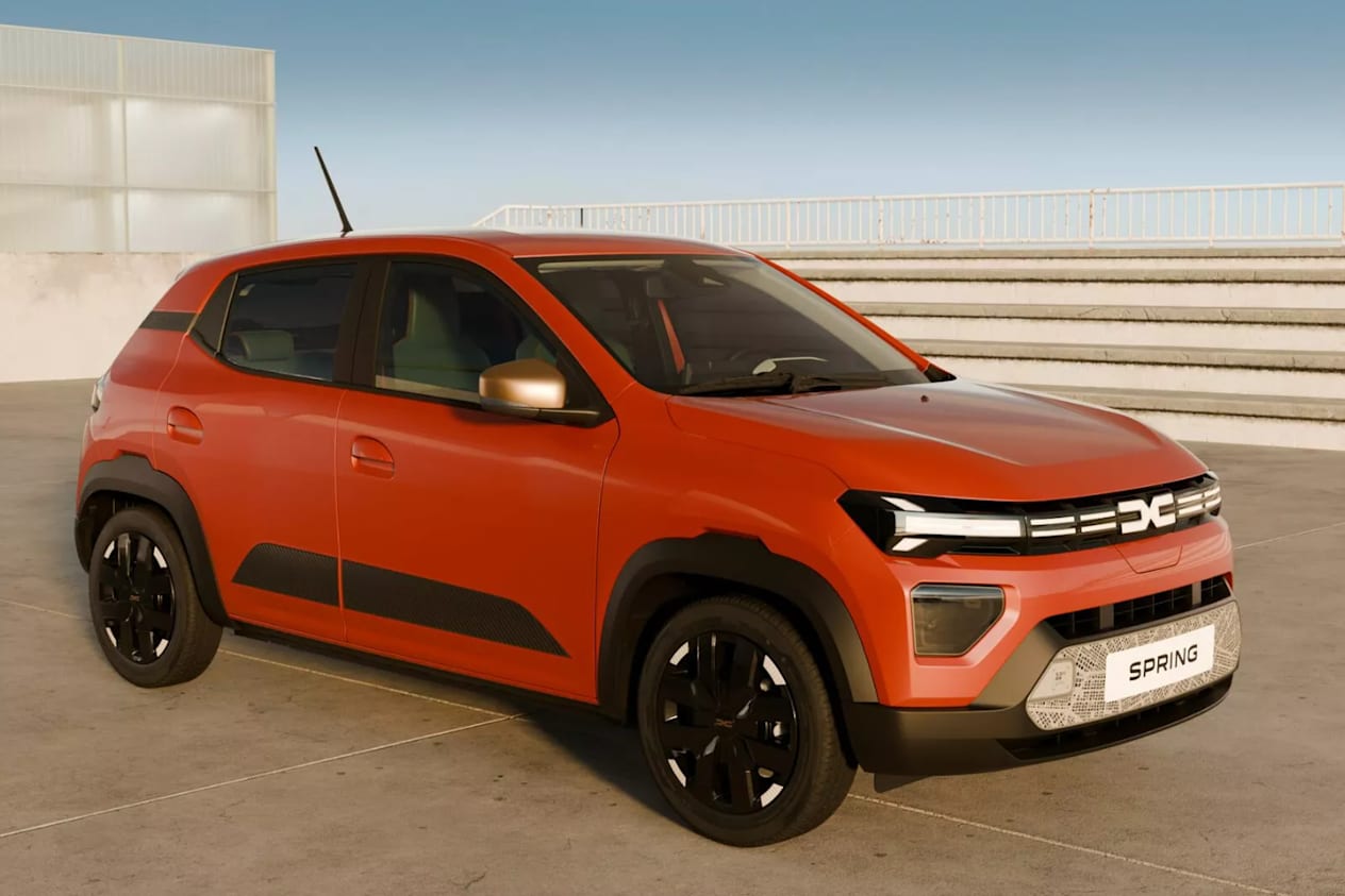 Side and front view of an orange Dacia Spring in an open concrete area