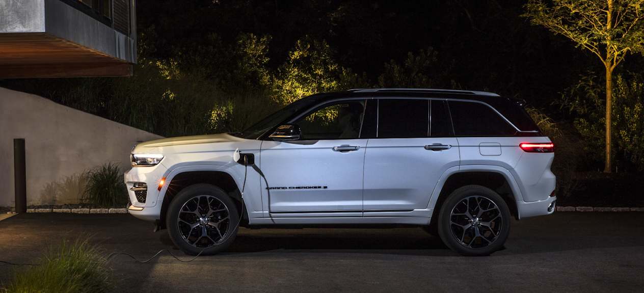 Jeep Grand Cherokee (2022) : De profil et en recharge face à une maison