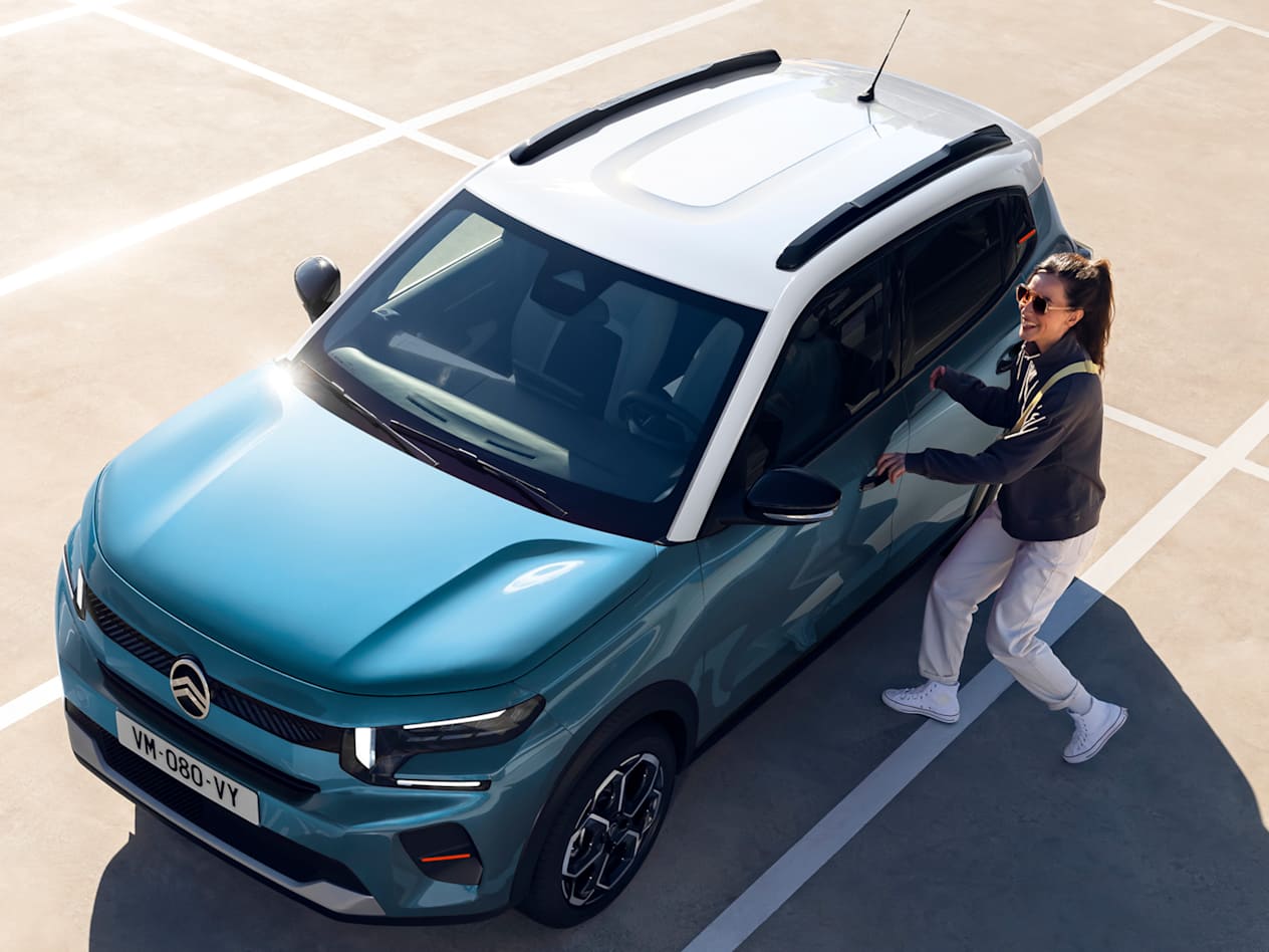 Citroën C3 2024 bleue : trois quarts avant gauche vue plongeante avec un couple sur un parking