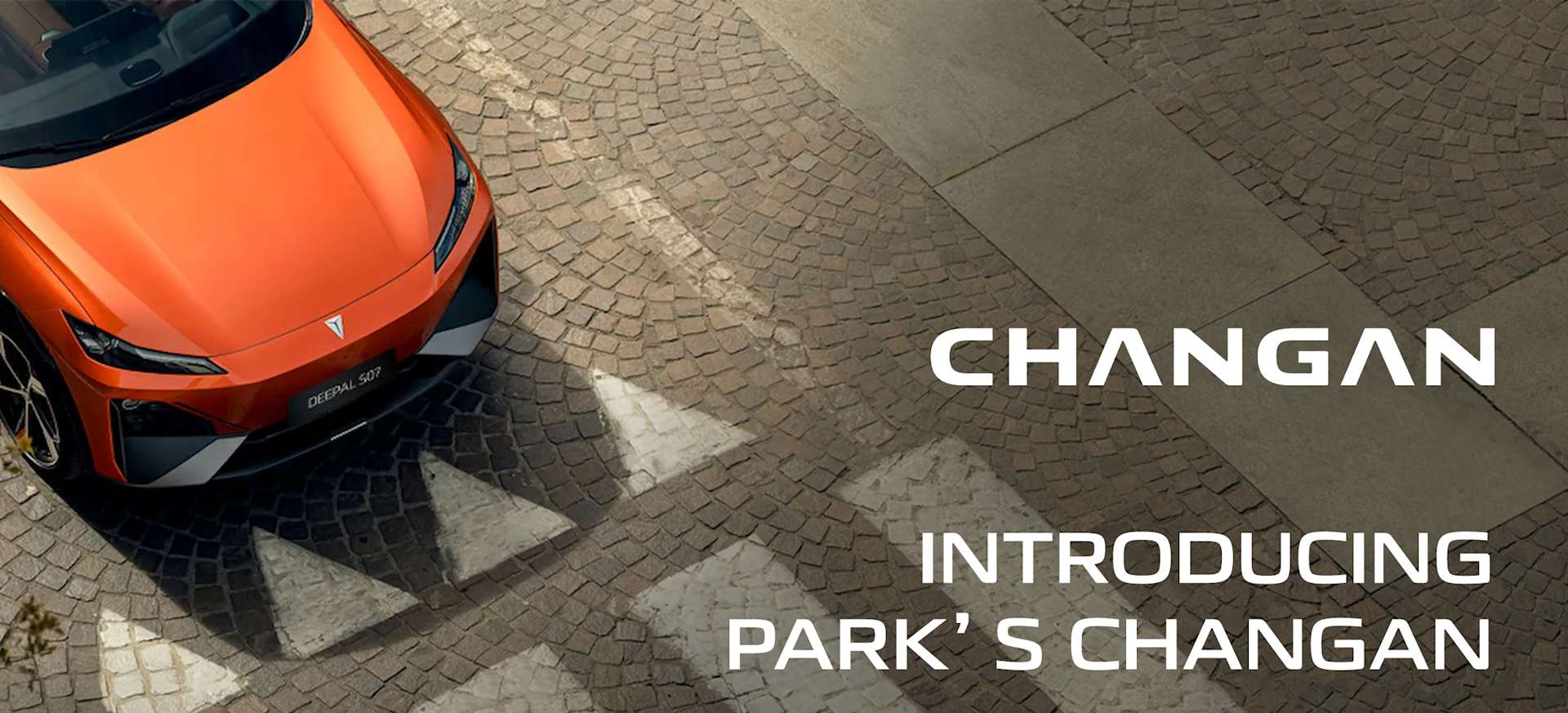 An aerial view of an orange Changan Deepal parked on a cobblestone street with directional markings.
