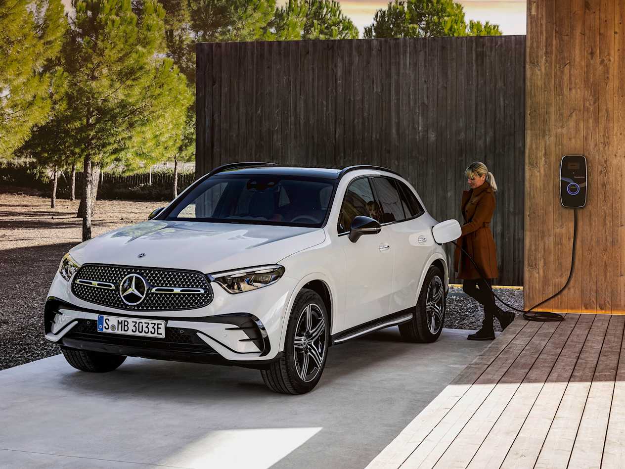 Mercedes-Benz GLC 2022 : Trois quart avant gauche avec une femme qui branche la prise de recharge