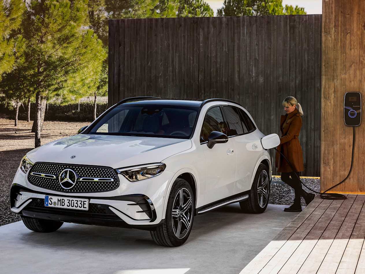 Mercedes-Benz GLC 2022 : Trois quart avant gauche avec une femme qui branche la prise de recharge