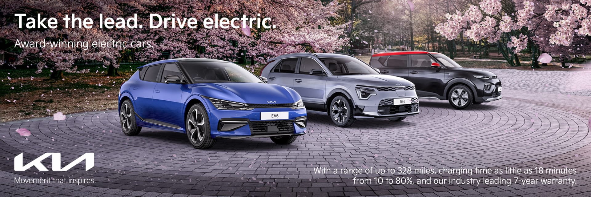 Range of Kia Electric vehicles parked in front of trees with pink blossoms