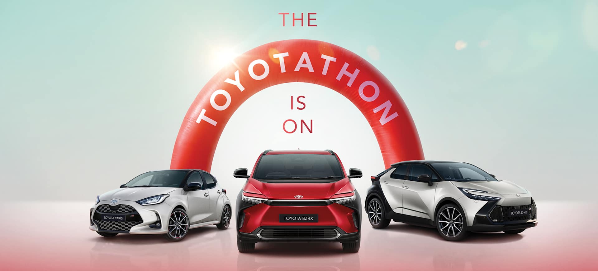 Three Toyota cars displayed under a large red arch with the text "THE TOYOTATHON IS ON."