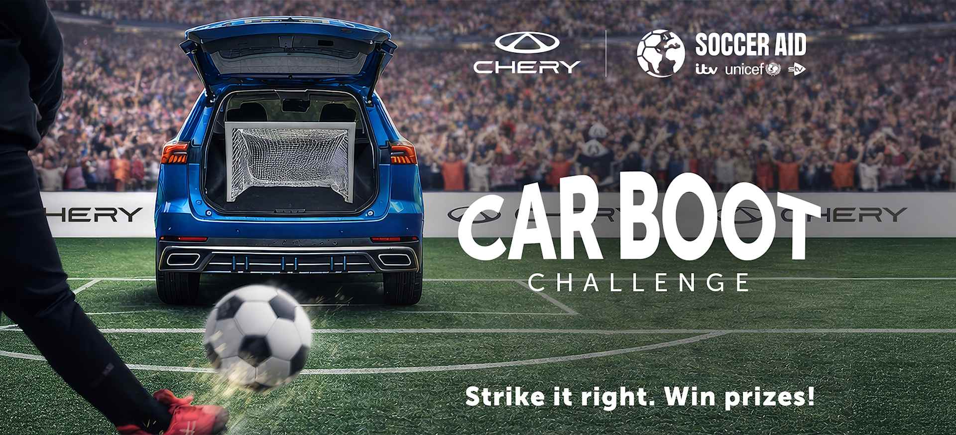 A footballer kicks a ball towards a car boot set up as a goal in a stadium filled with spectators.