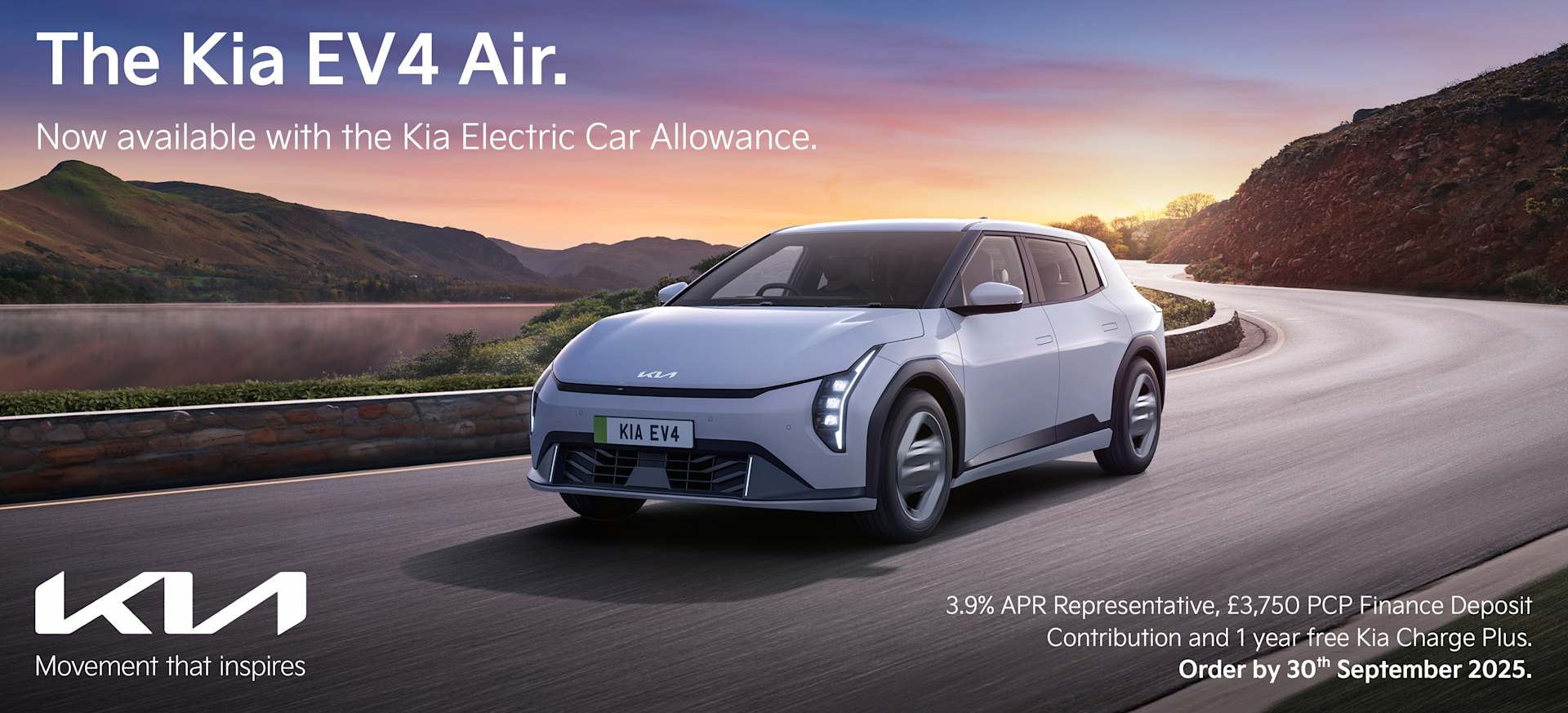 A Kia EV4 Air electric car driving on a scenic road with mountains and water in the background.