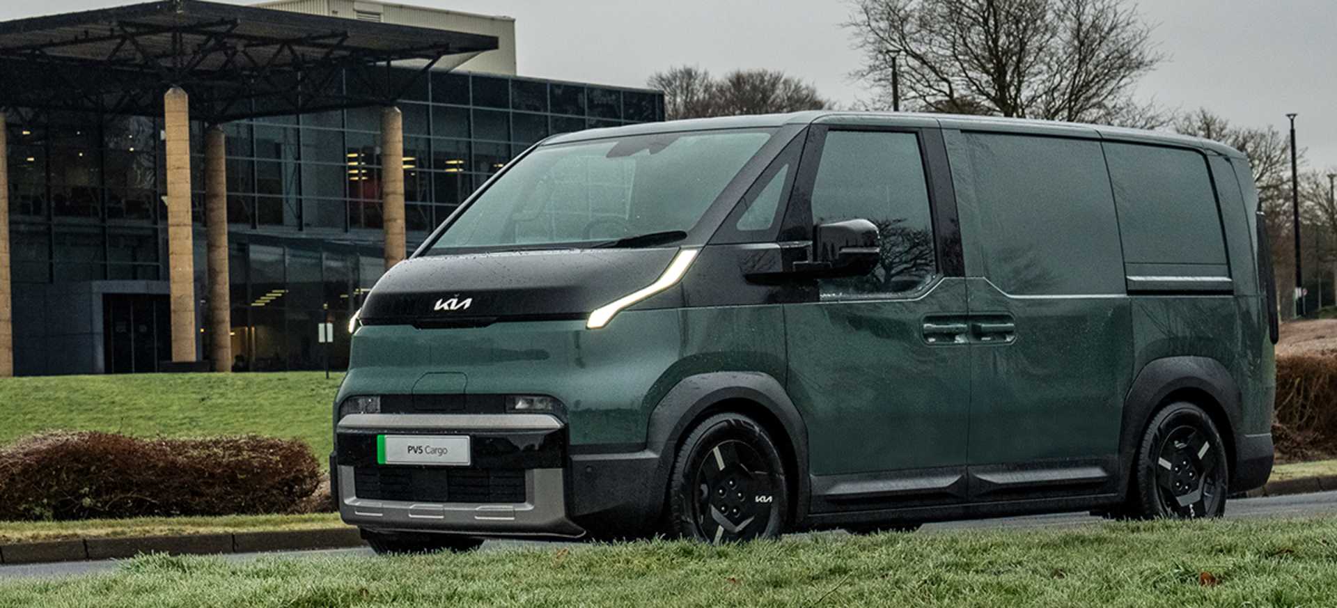 A modern green Kia PBV 5 Cargo van parked on a road near a contemporary building with large glass windows.