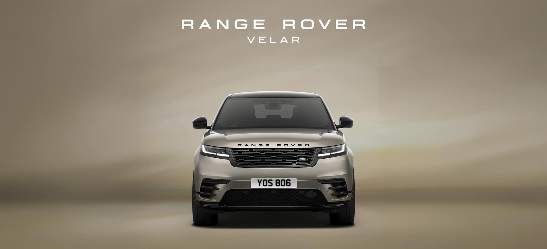 Front view of a Range Rover Velar against a soft beige background, showcasing its sleek design.