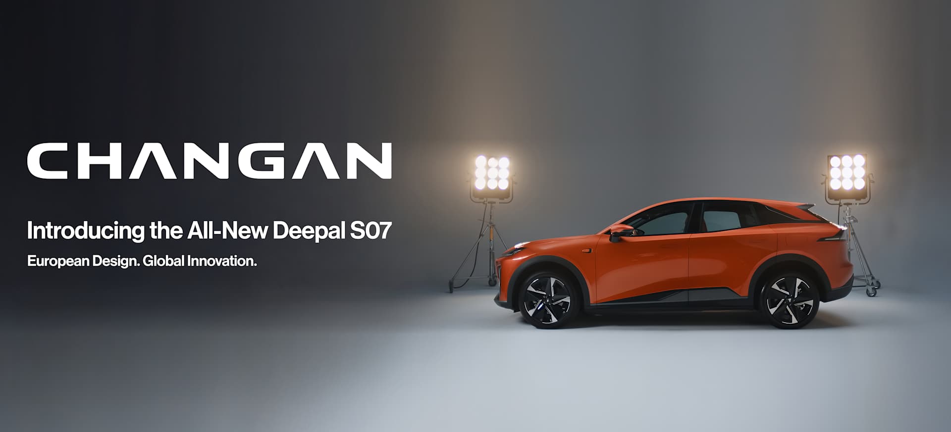 An orange car displayed under bright studio lights against a dark background.