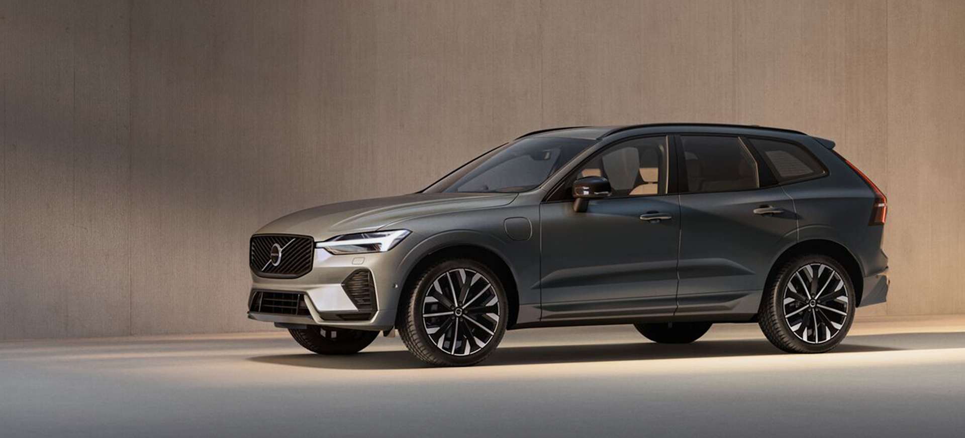 A grey Volvo SUV with stylish alloy wheels, parked against a minimalist backdrop.