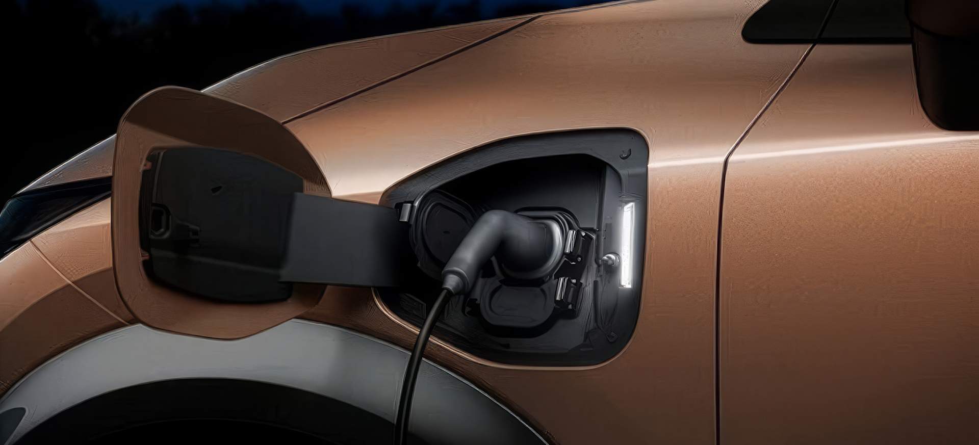 Close-up of an electric vehicle charging port with a cable connected, set against a dark background.