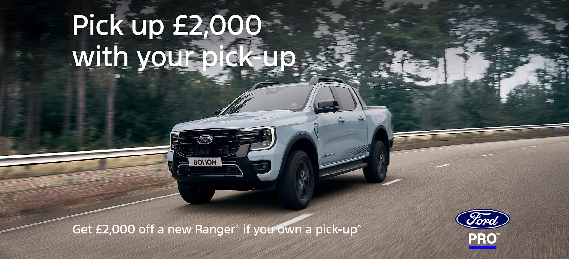 A light blue Ford Ranger pick-up truck driving on a tree-lined road.