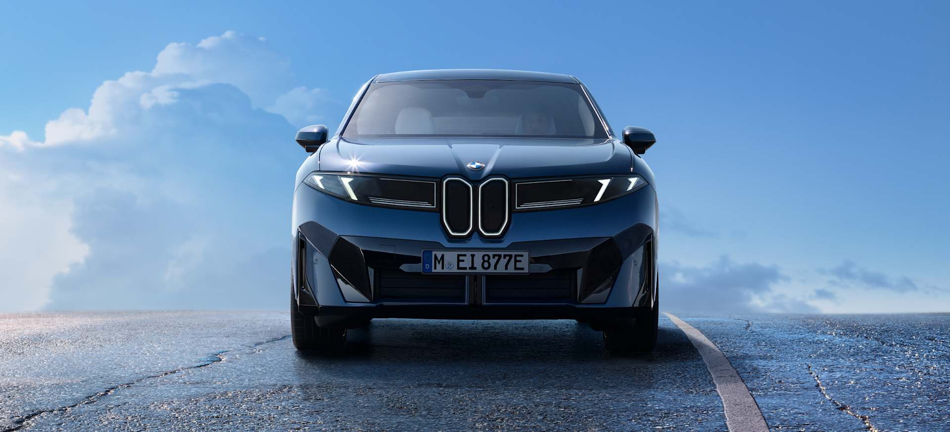 The all-new BMW iX3 facing the viewer, set against a clear blue sky.