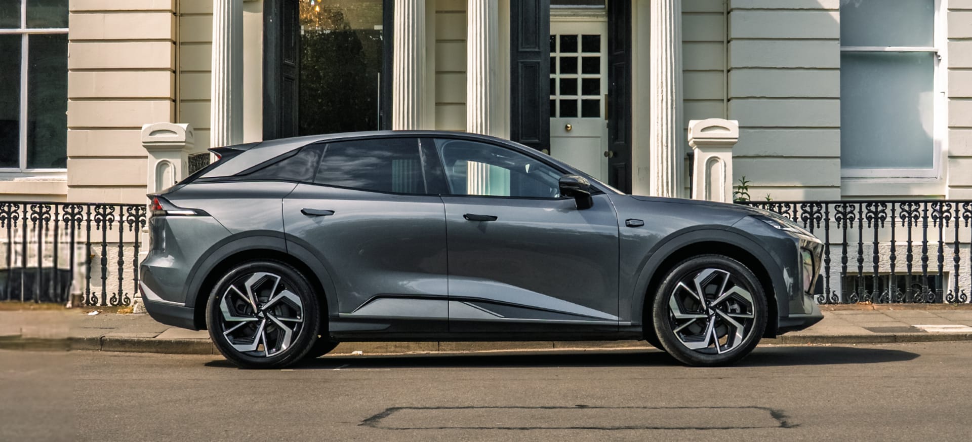 A sleek grey Changan Deepal SO7 parked on a street in front of a classic building with columns.