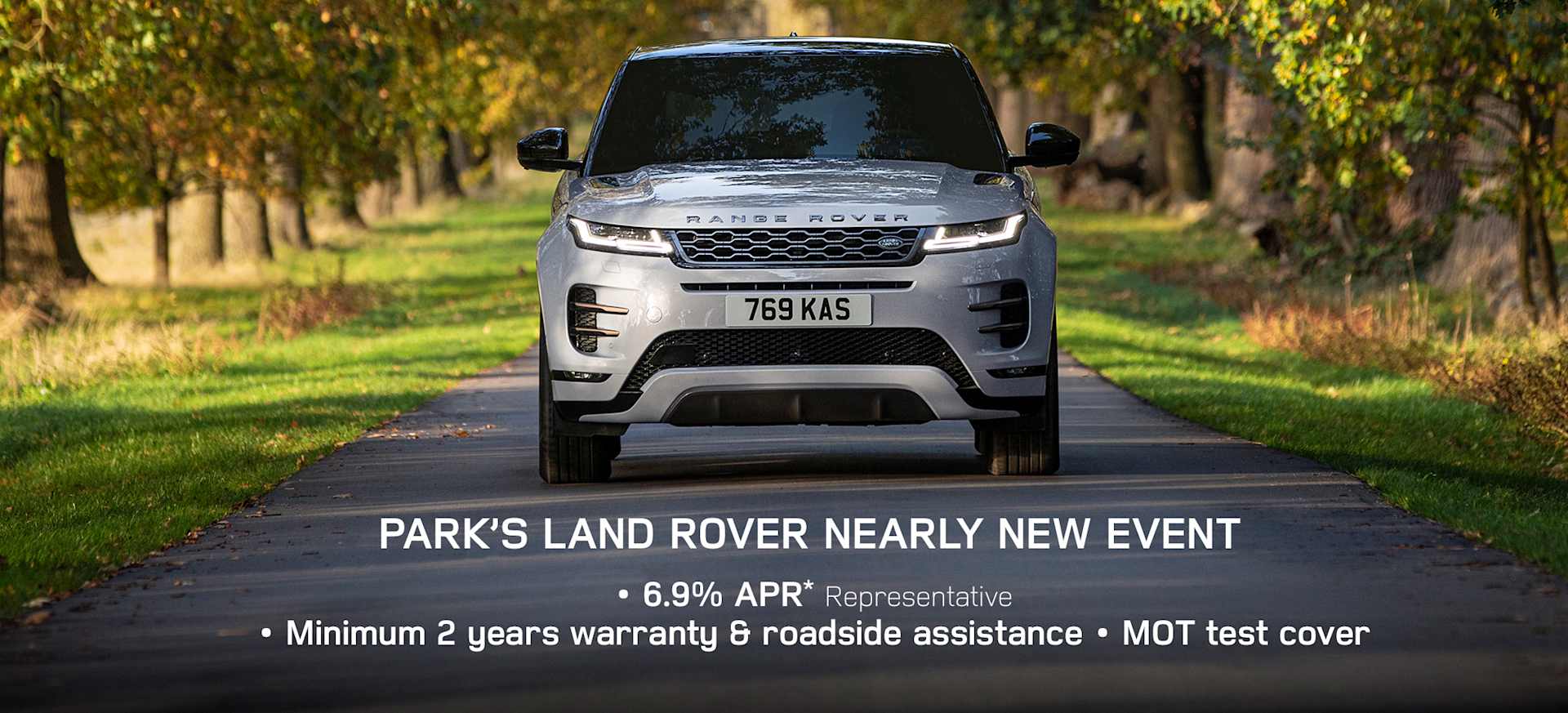 A silver Range Rover driving on a tree-lined road, promoting a nearly new event with offers.