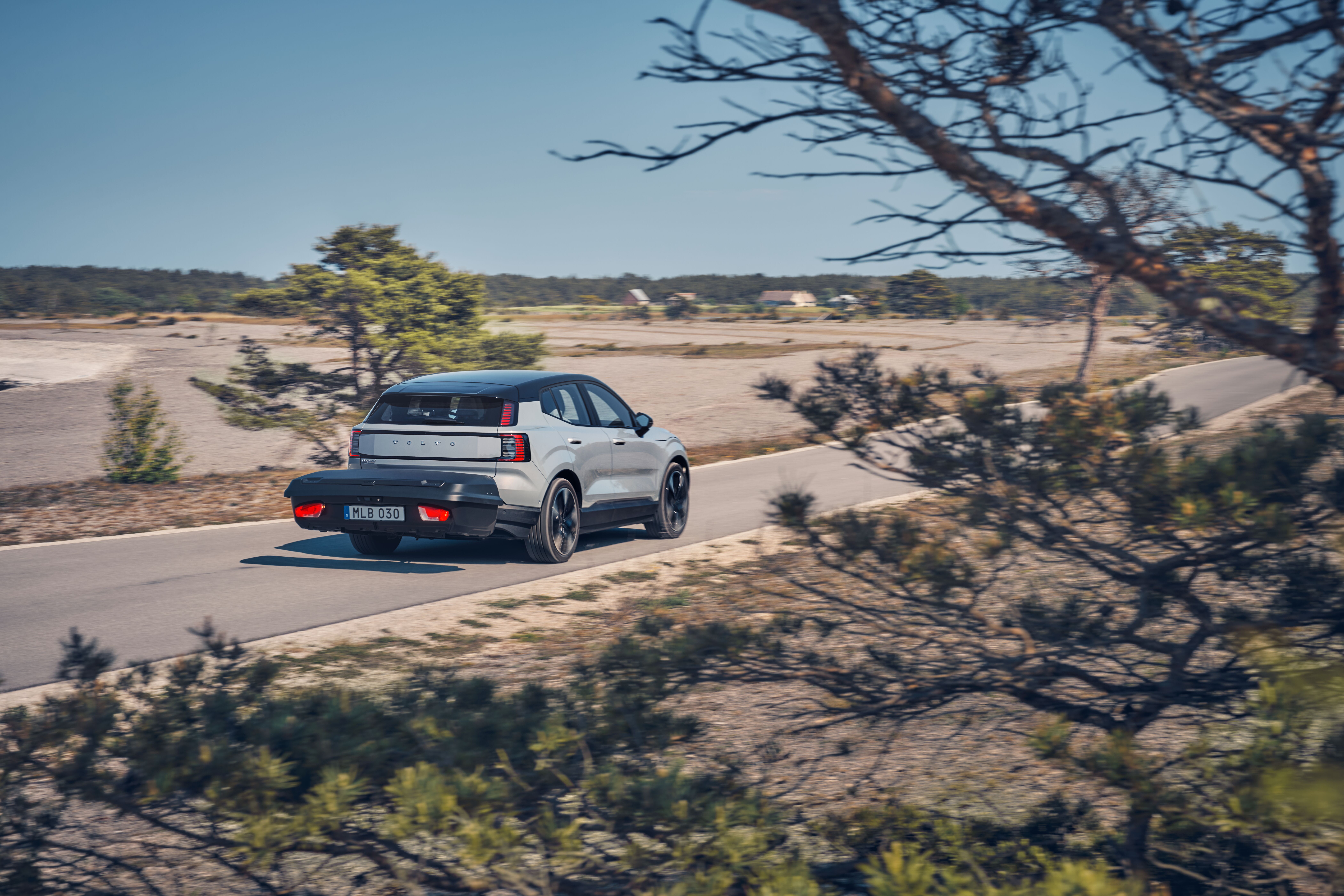 Volvo with a towbar cargo box beside a country track
