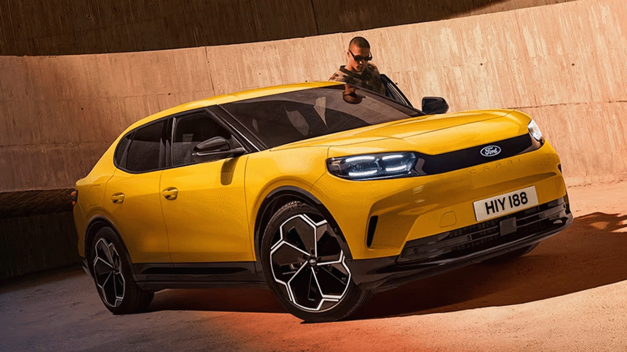 A bright yellow Ford car parked against a textured wall, with a person standing beside it.