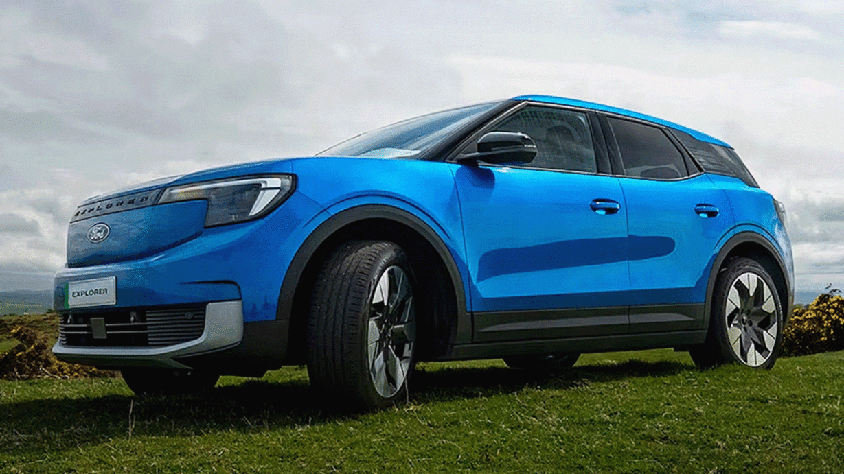 A blue electric SUV parked on green grass with a cloudy sky in the background.