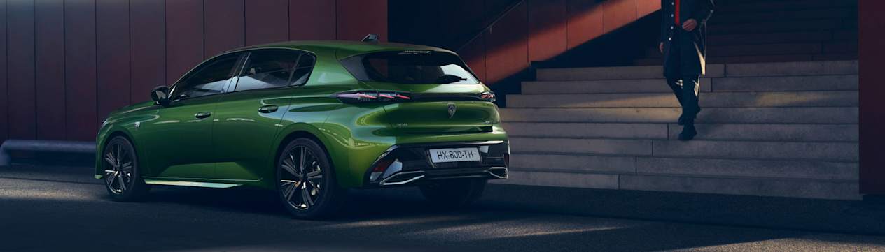 Peugeot 308 2021 verte : trois quarts arrière gauche garée devant un immeuble