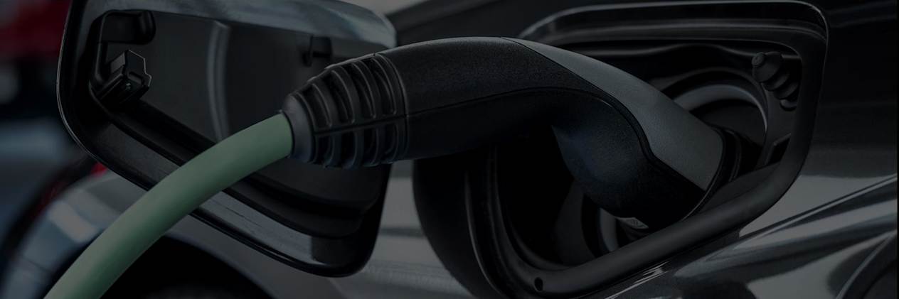 Black and green EV charging connector plugged into a black car