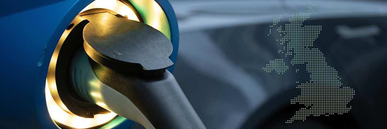 Close up of a lit up EV charging connector plugged into a blue car