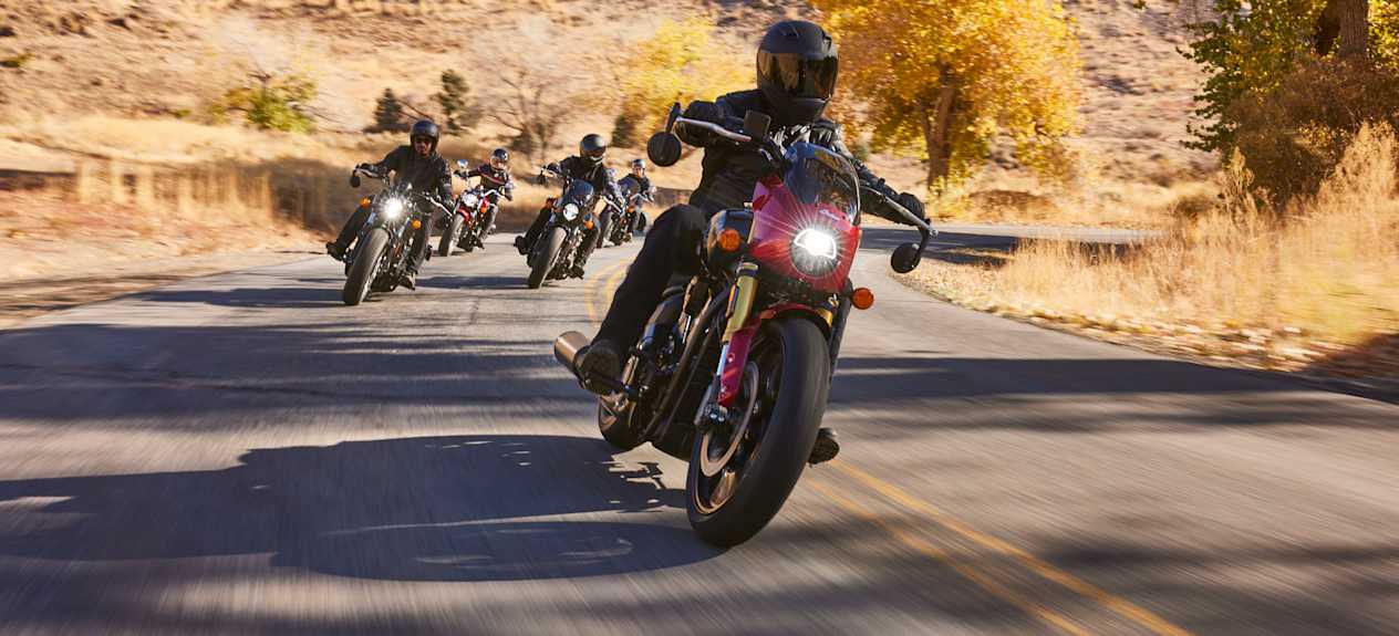 Indian Scout 101 2025 Sunset Red Metallic : face avant sur route avec groupe de motards