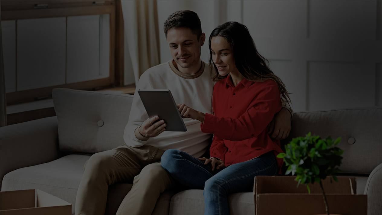A man and woman sitting on a sofa looking at a tablet together