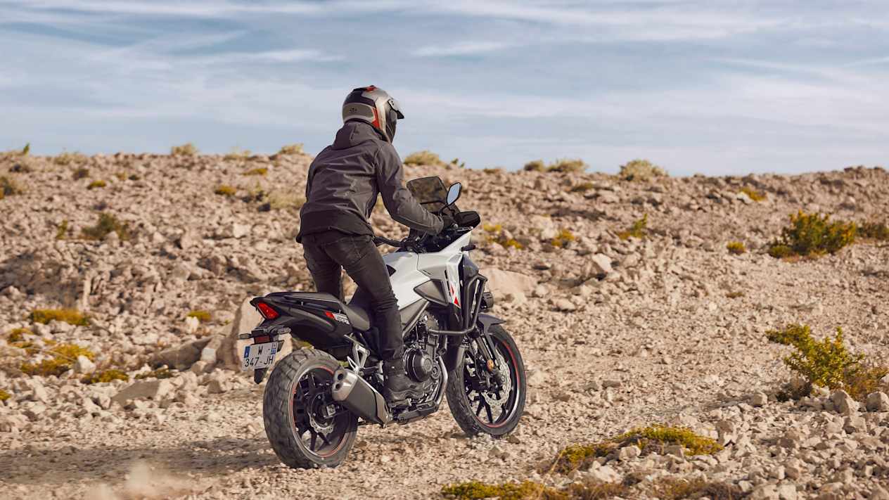 Honda NX500 2024 : trois quarts arrière sur piste de cailloux