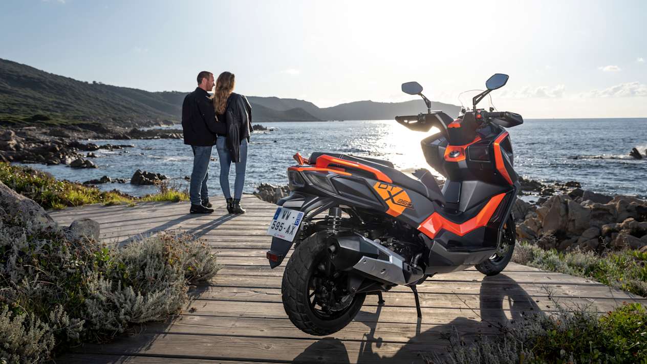 Kymco DTX 360 2024 : trois quarts arrière droit statique en bord de mer