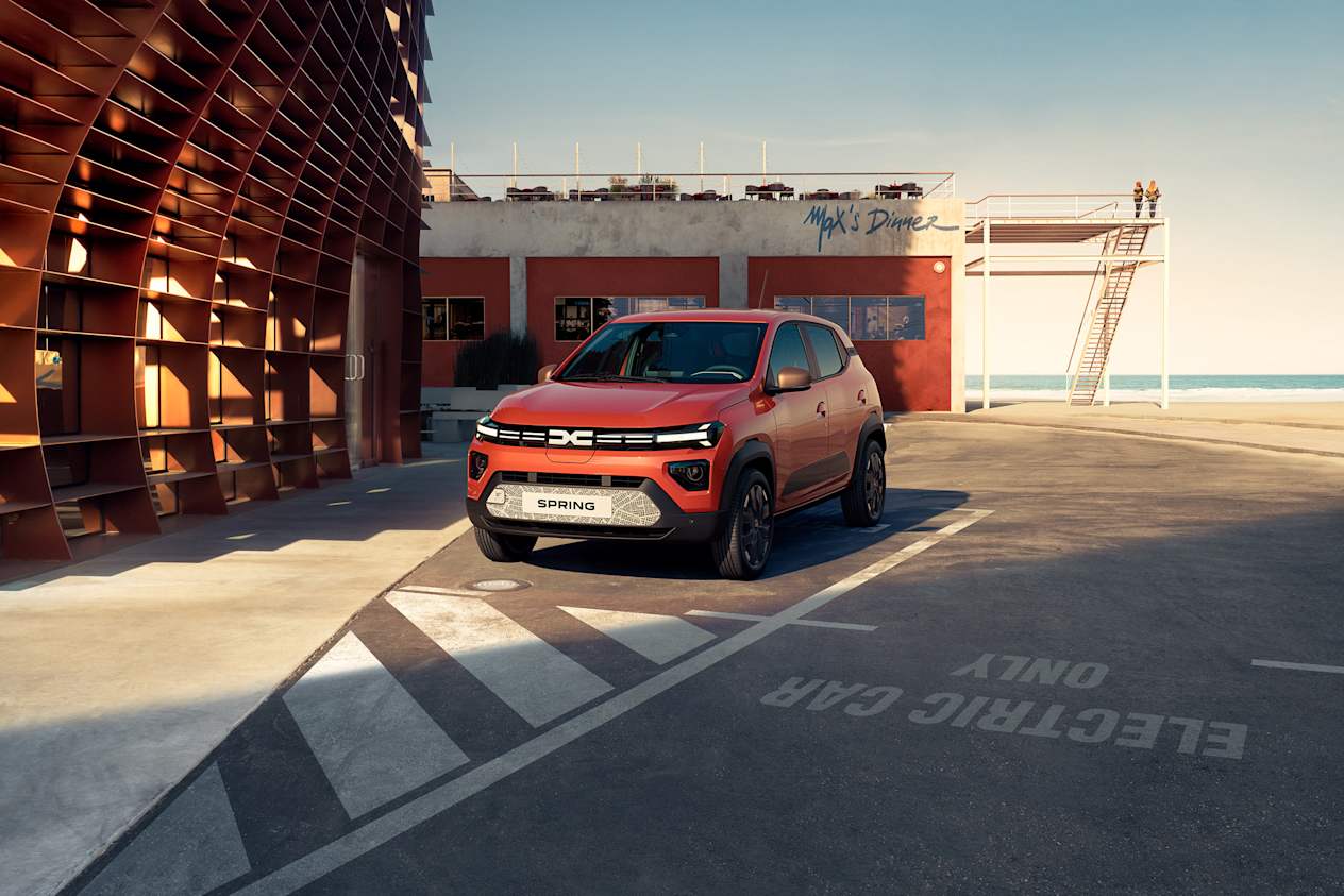 An orange Dacia Spring parked in an open industrial area