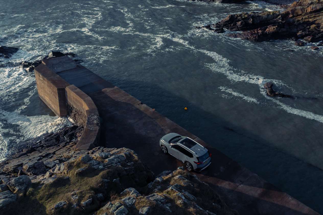 Aerial view of a grey Nissan X-Trail next to the sea