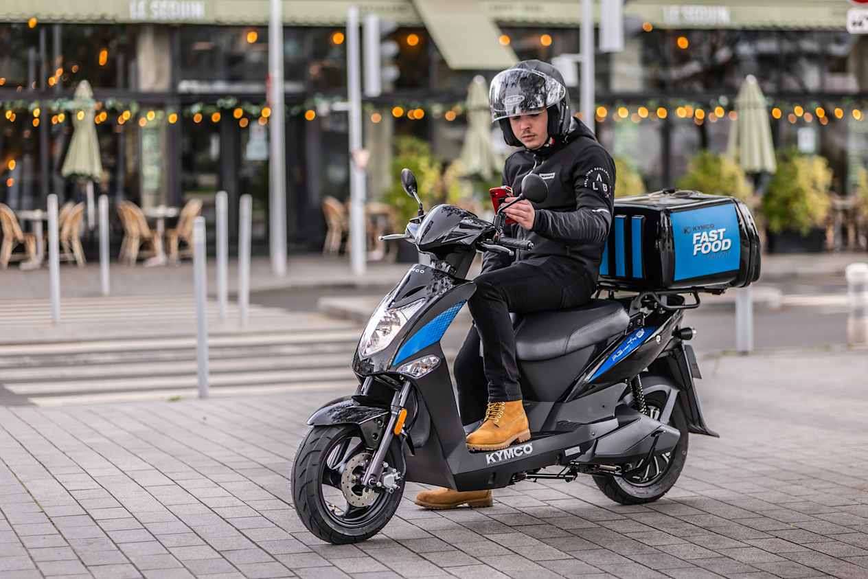 Kymco Agility EV 2024 : trois quarts avant gauche statique avec livreur