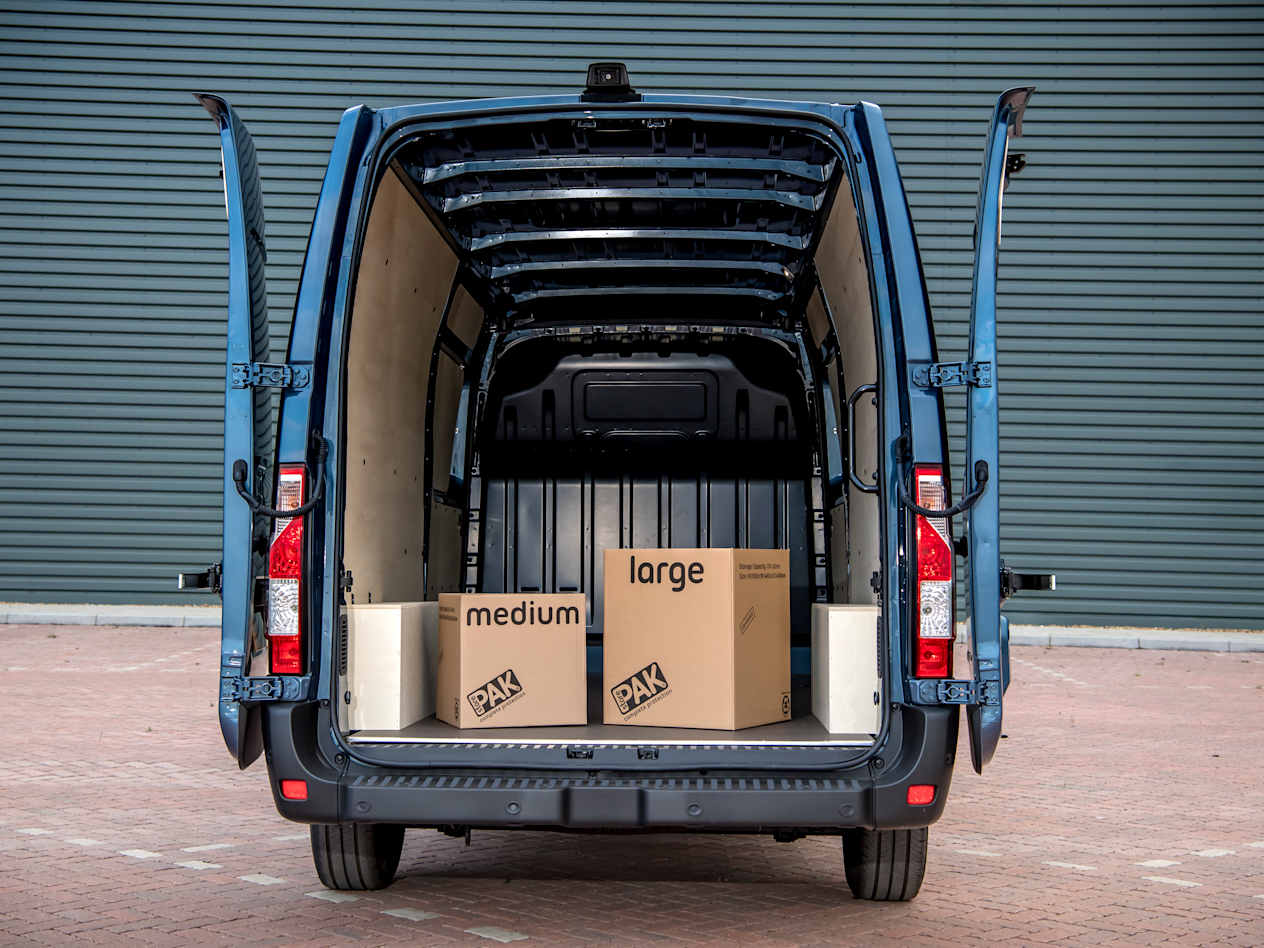 The rear of a blue Renault Master with the doors open and the cargo space filled with boxes