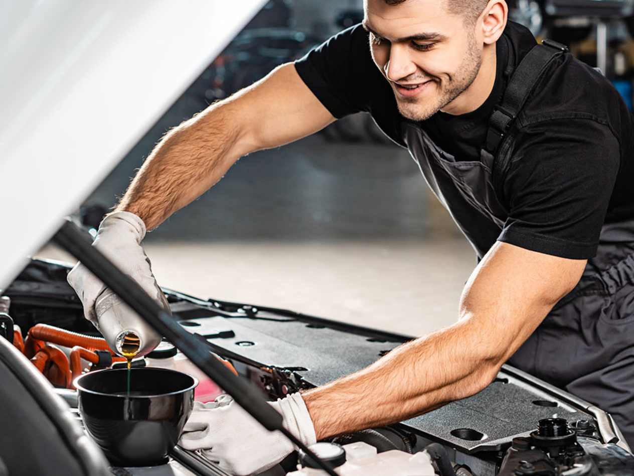 Croxdale vehicle technician wearing black overalls pouring oil into a vehicle